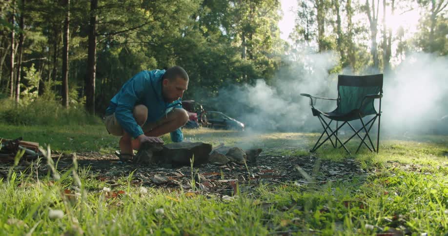 White man starting a bonfire by blowing the smoke