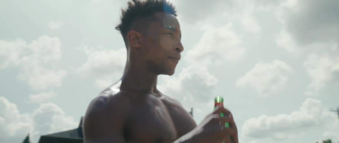 Young muscular fit man drinking water from a bottle outdoors