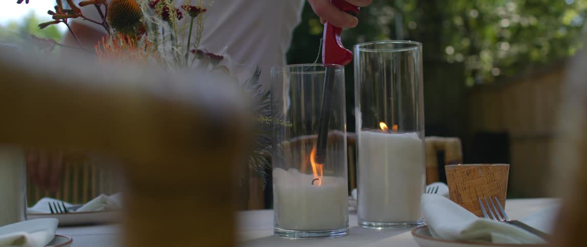 A person lighting candles at a table outside
