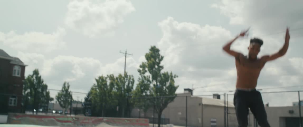 Shirtless black man roller blading in an empty skate court