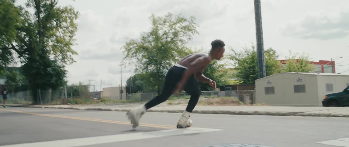A man is rolling blading on a street without a shirt