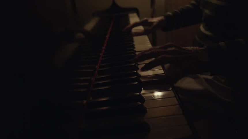 A man is playing the piano in a dark room