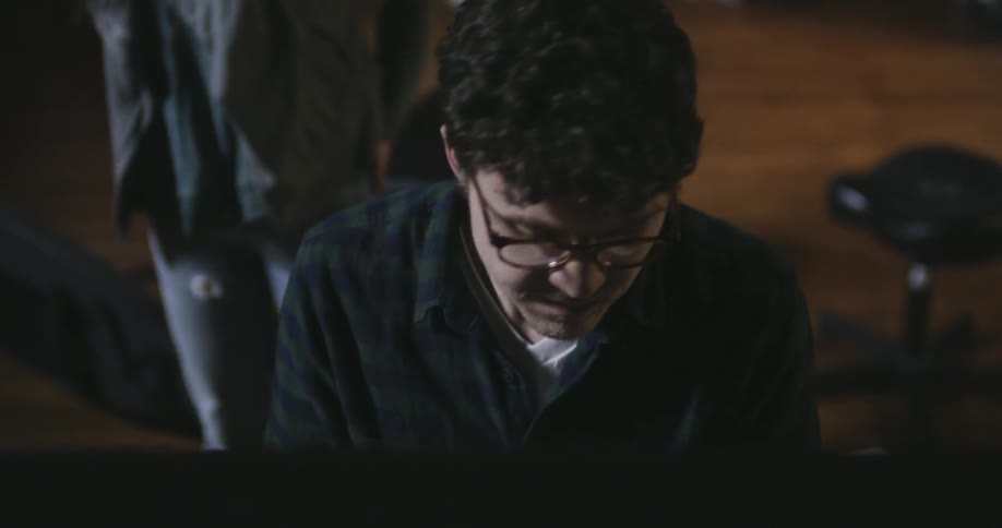 Spectacled man appearing to be playing a piano