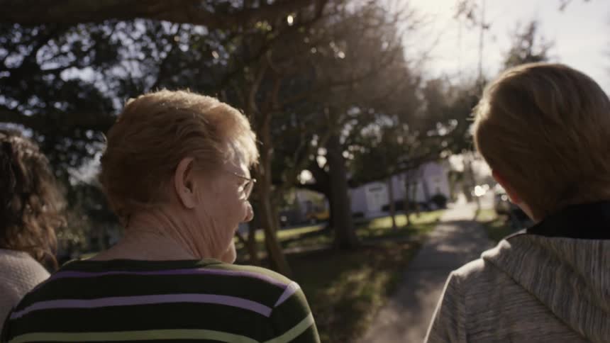 Three women are walking on a sidewalk together