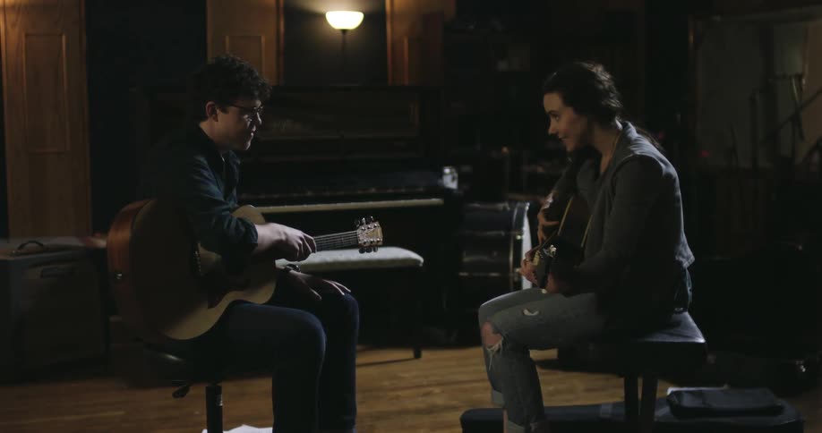 A man and women are talking and playing guitars