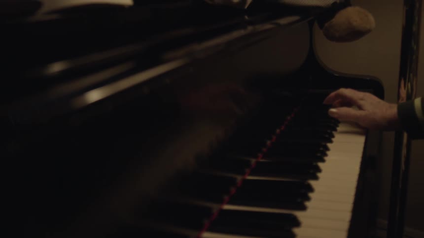 An older female strikes a key on a piano
