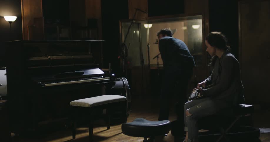 A man and woman playing instruments in a dim room