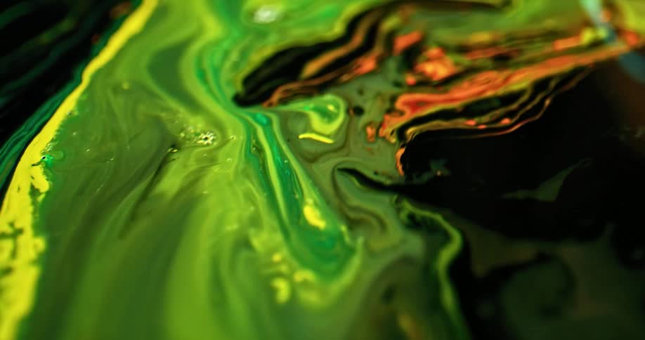 A stream of bright green liquid flows quickly and mixes and swirls with other colors of liquid