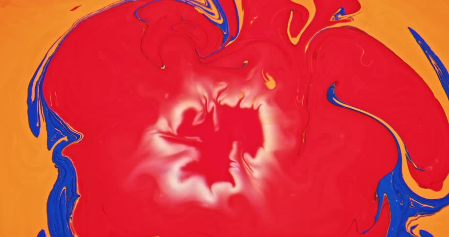 Bright red liquid ink forming abstract patterns pouring into blue and orange in k