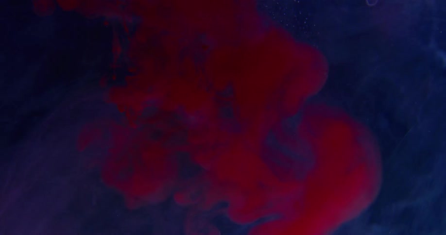 Bright red liquid ink clouds inside a dimly lit water tank
