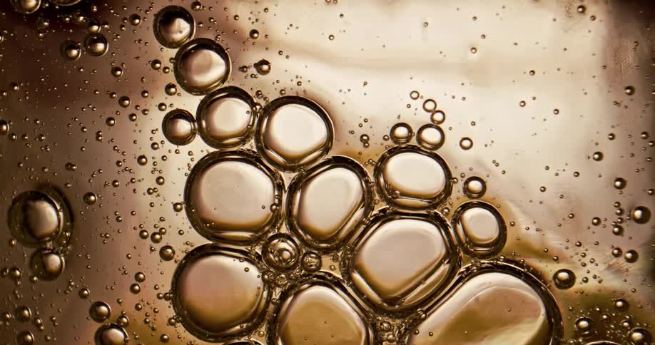 Microscopic view of a light brown liquid with bubbles moving downwards