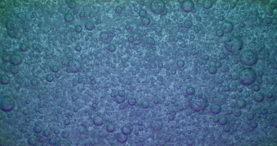 Bubbles of varying sizes rise up in a blue liquid