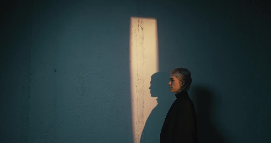 Young woman modeling near a wall inside a dimly lit room