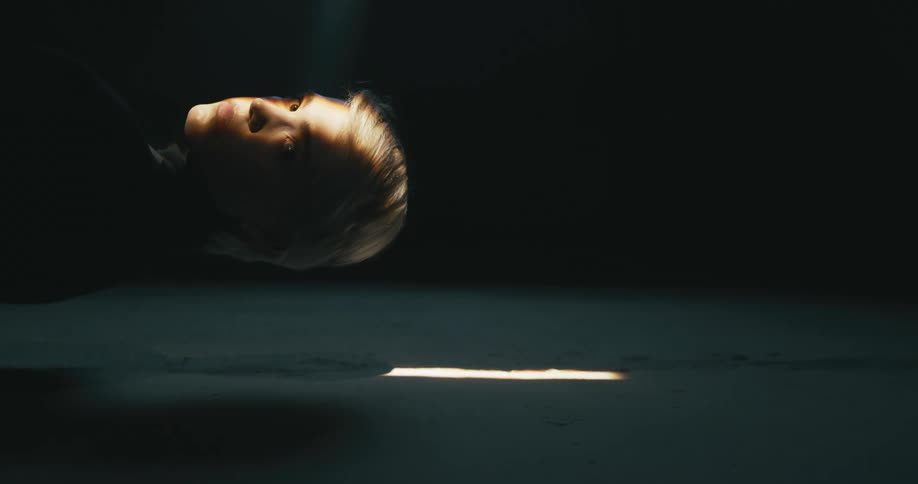 Short haired blonde woman looking at the camera inside a dimly lit room