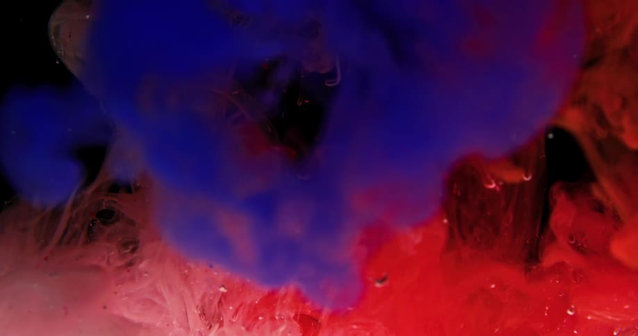 Colored powders fall and expand as they are dropped into a vat of liquid