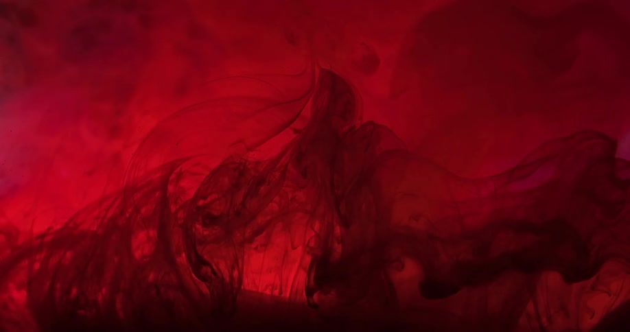 Strings of black liquid ink swirling and flowing in a tank of red bright ink