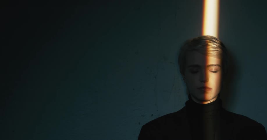 Young short haired blonde woman model looks at the camera in a dimly lit room
