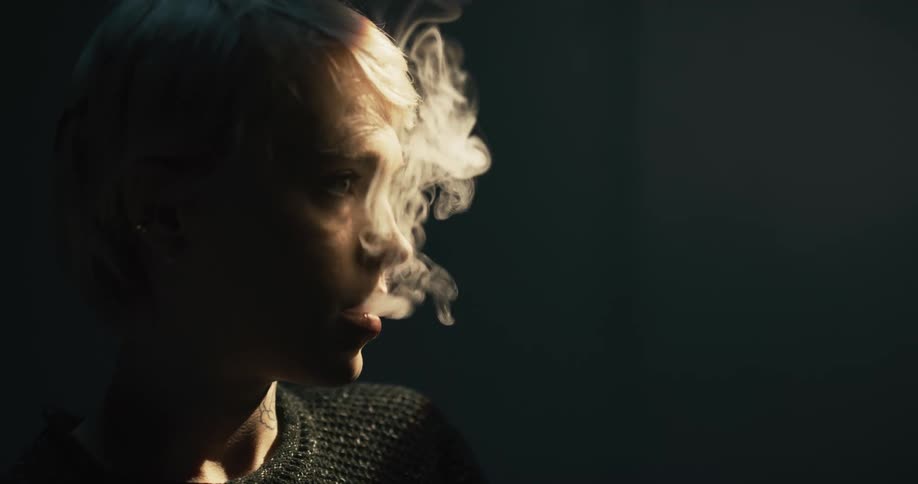 Blond woman exhales smoke from her mouth