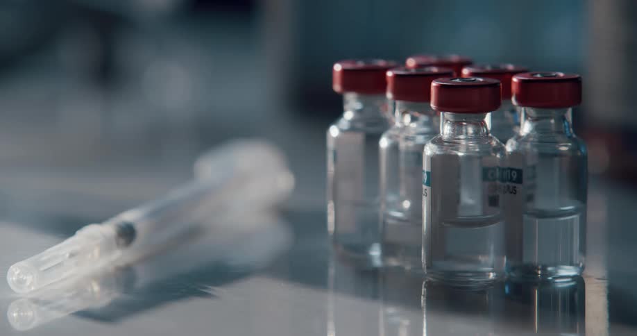 A syringe and bottles of a vaccine on a counter top