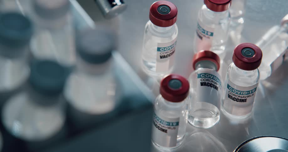Several glass vials that are sitting on a counter are labeled as vaccine