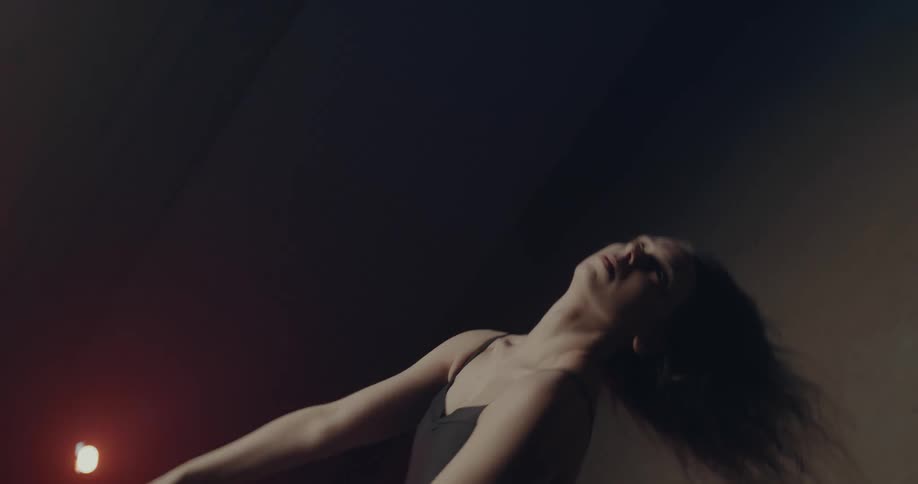 A woman in a room dancing and stretching with lights in the background