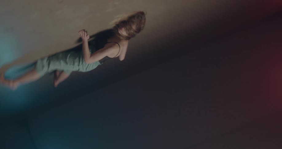 A woman in a room dancing and tumbling on the floor with lights in the background