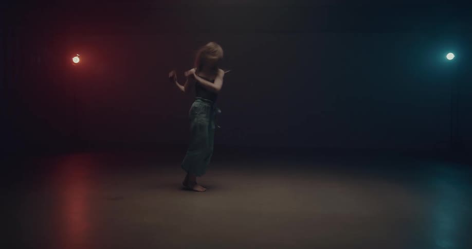 White woman dancing alone in the middle of a dark empty room