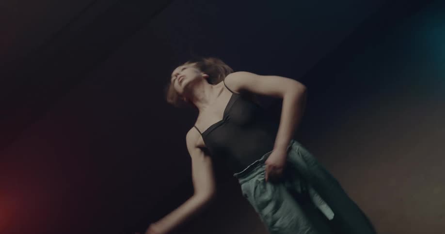 Young long haired woman dancing on a dimly lit stage