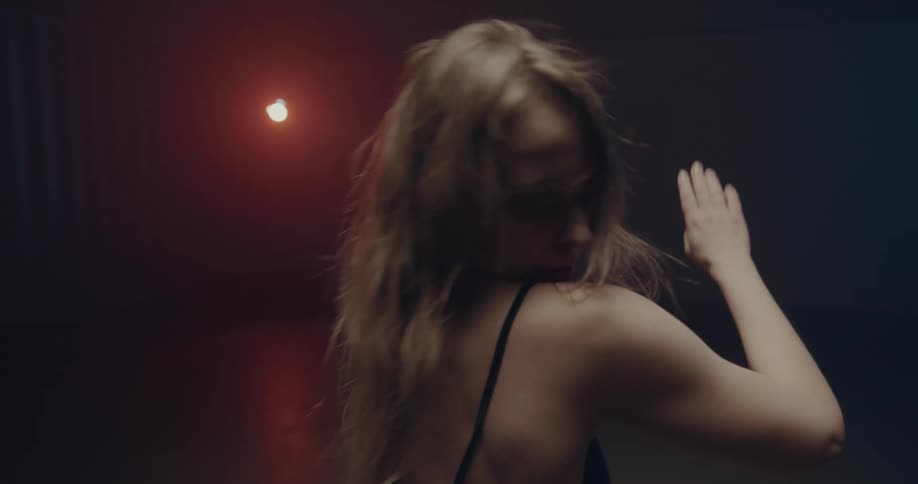 White woman dancing alone in a dark room