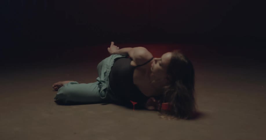 A woman in a room dancing and stretching on the floor