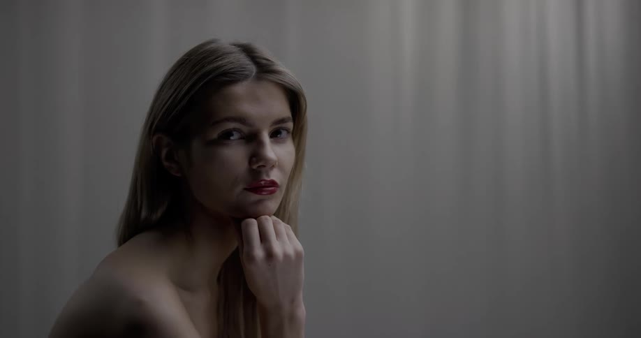 A young woman is sitting indoors while posing for the camera