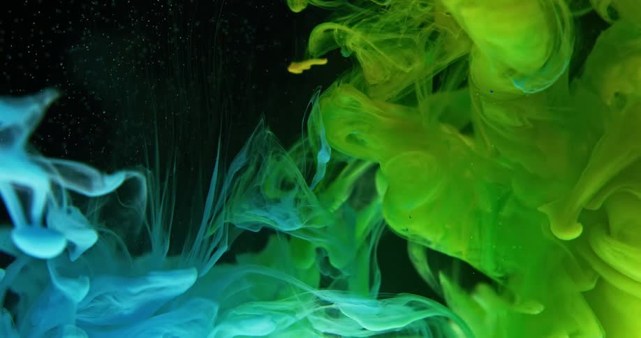 Green yellow and blue smokes submerge into a liquid in a black backdrop