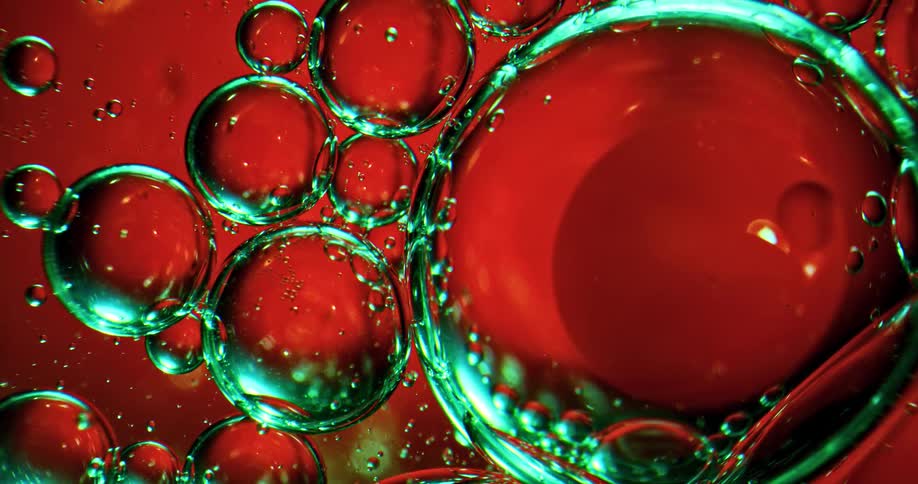 Glowing bubbles float and pop in red liquid