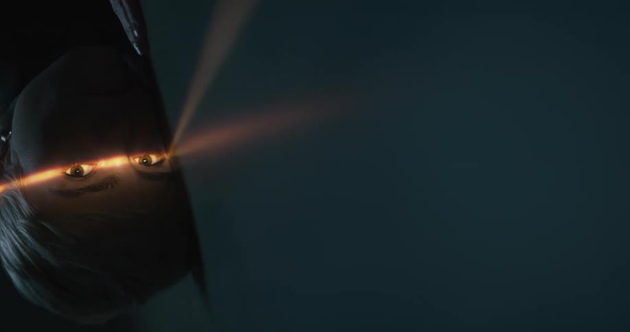 A woman resting her head opens her eyes in a beam of light in a dark room