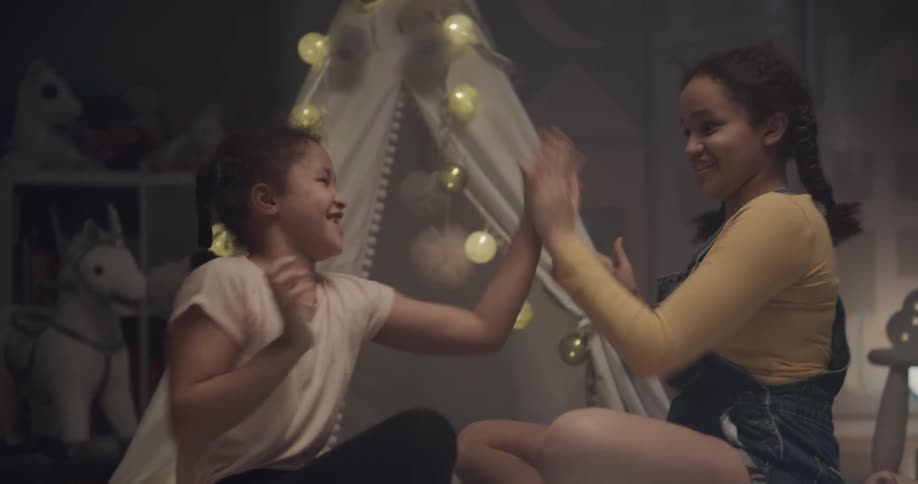 Sisters playing hand clapping games in a bedroom at home