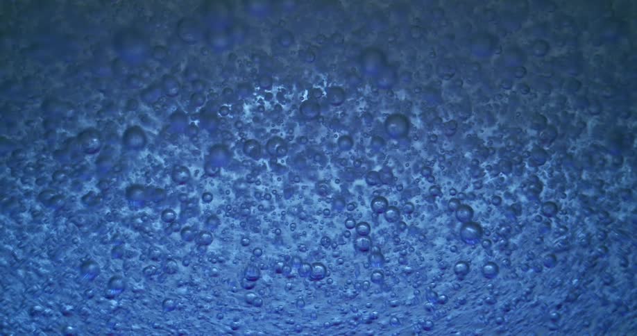 Bubbles slowly rise through light blue fluid