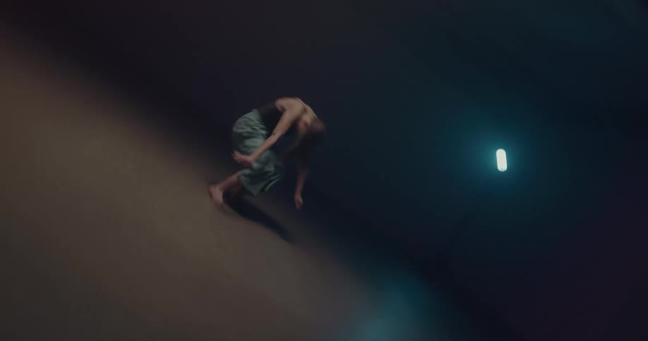 A woman performs a cartwheel over a dimly lit stage