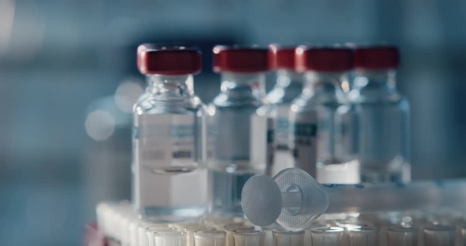 A syringe lies next to bottles that are sitting atop tubes