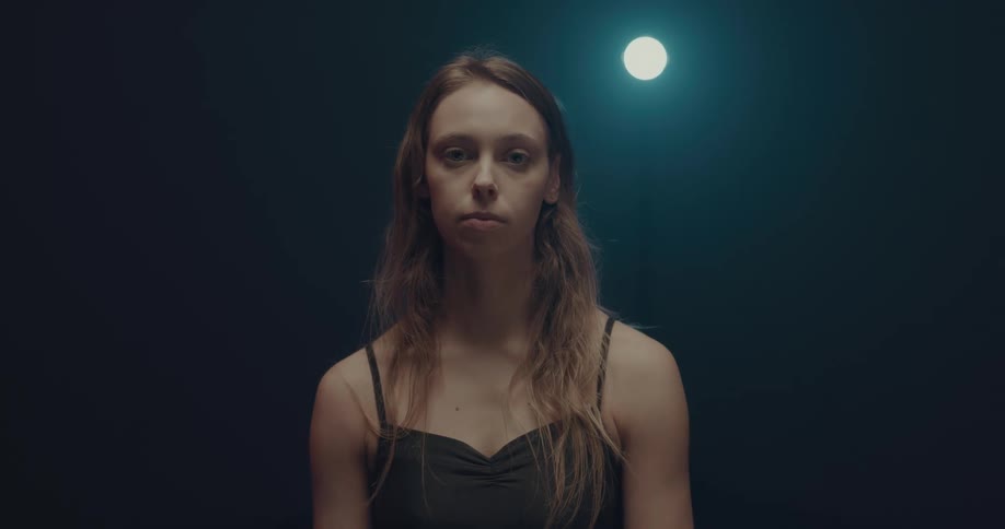 A woman standing while the camera pans out and goes out of focus