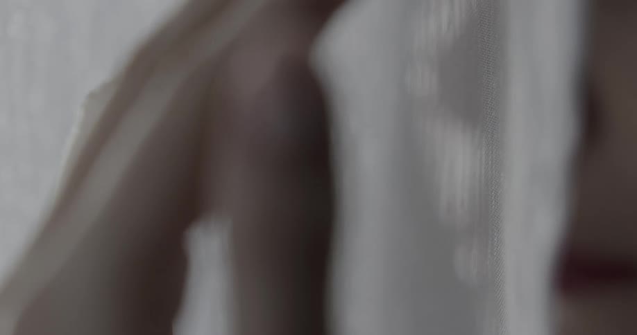 A womans hand touches white fabric in close up