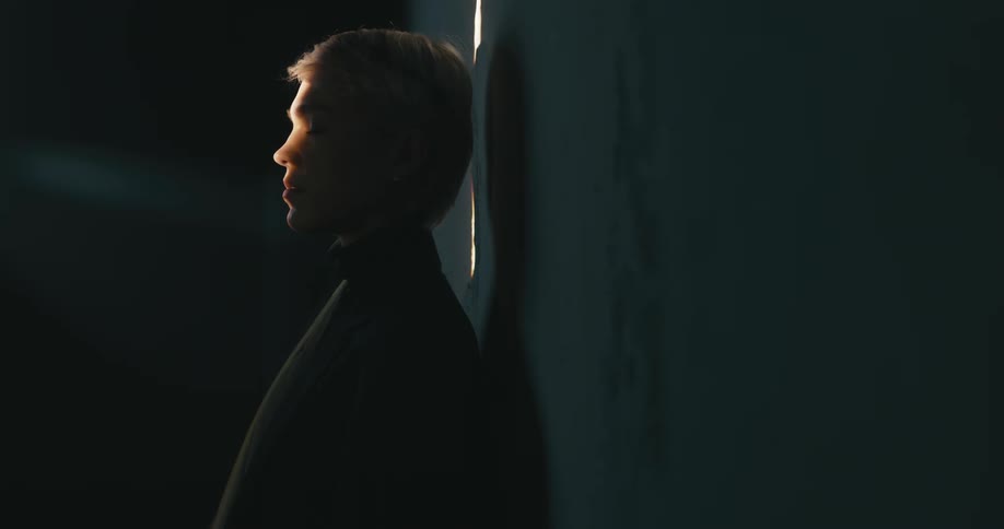A woman standing in a room next to a wall with the sunlight shining on her face