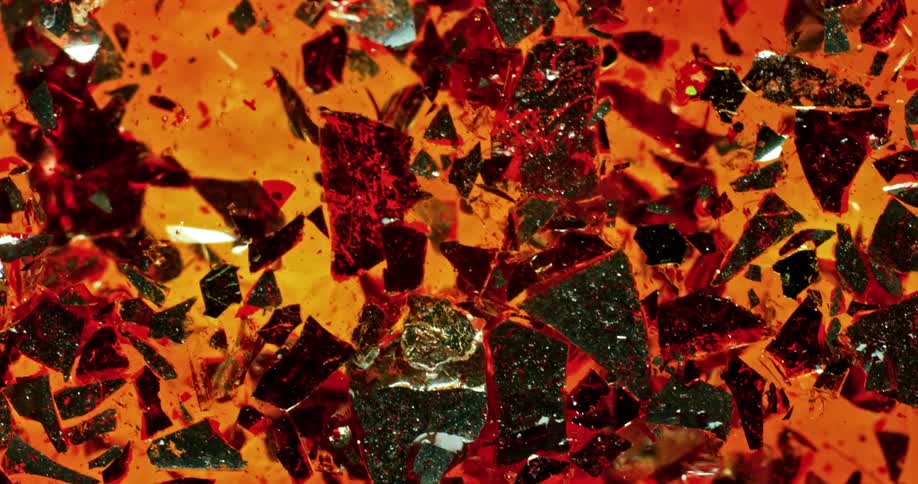 An orange liquid substance with broken shiny sparkly pieces floating and sinking