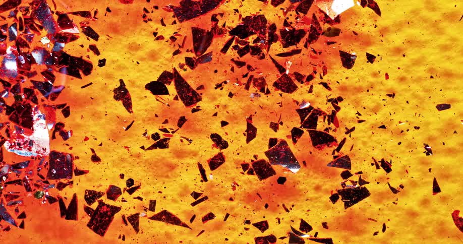 Broken up red shiny pieces being moved around in an orange liquid