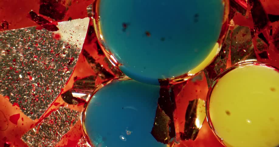 Pieces of broken glass floating on liquid red ink with yellow and blue bubbles