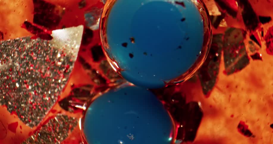 An orange liquid with pieces of broken materials and blue bubbles inside of it