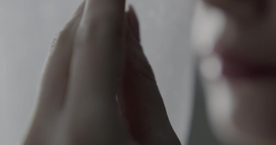 A woman gently touches a sheer fabric curtain with her fingers