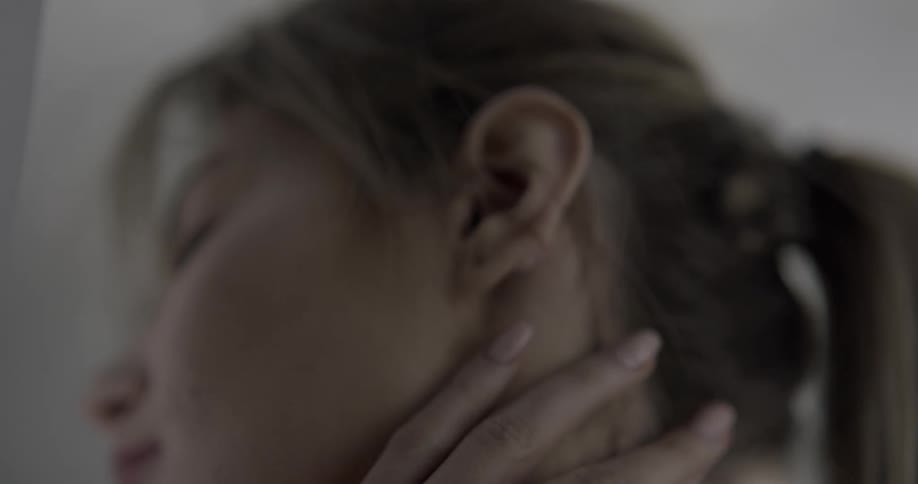 A woman caressing the side of her face and neck with her hand