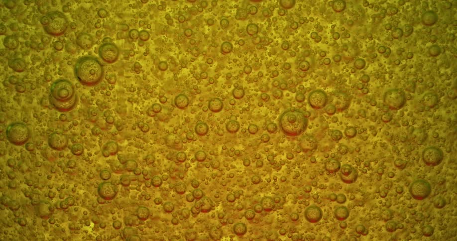 Air bubbles rising up on a thick yellow liquid