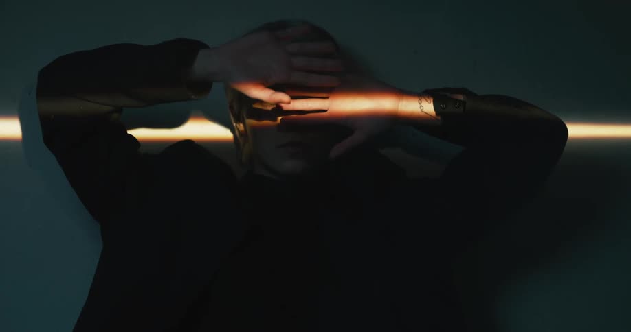 Young blonde short haired girl moving hands in front of her face inside a dimly lit room
