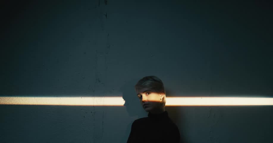 Woman in a dark sweater poses as a strip of light is across her eyes